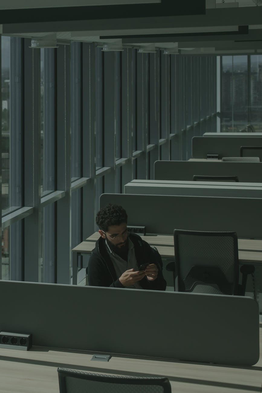 Modern open-plan office in Bogota Colombia with professionals working at desks, warm natural light through floor-to-ceiling windows, teal and green color palette, editorial architectural photography